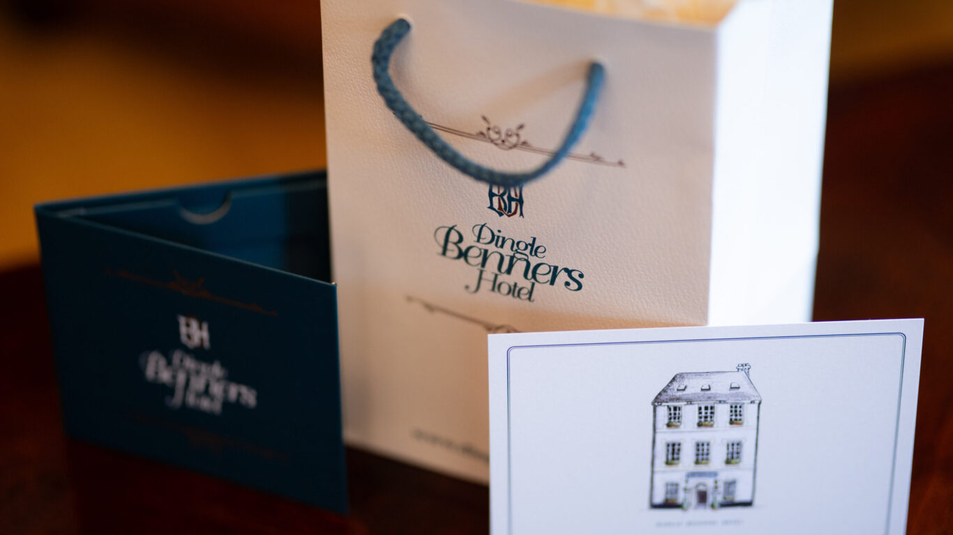 A white paper gift bag with blue handles labeled