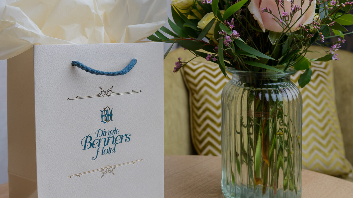 A gift bag, a glass vase with assorted flowers, and a blue folder labeled 