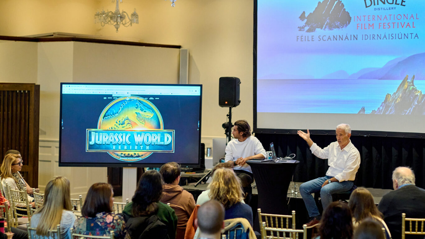 Guests enjoying a film screening and talk at the Dingle Film Festival, with elegant chandeliers and a large screen display.